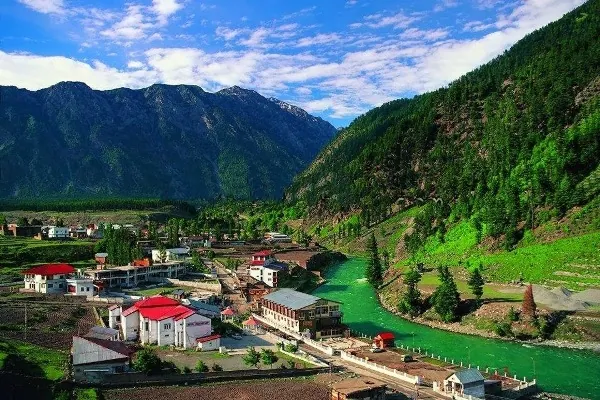 Red-roofed hotels beside a green river in a Murree and Galyat valley